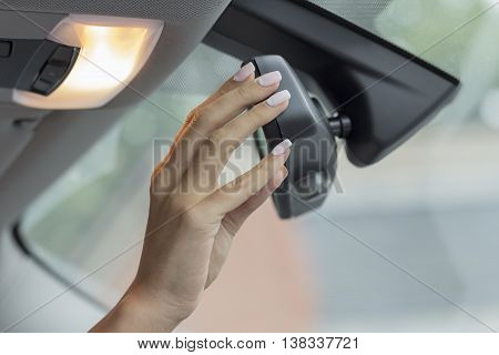 the girl in the cabin of the car  adjusts the rear view mirror
