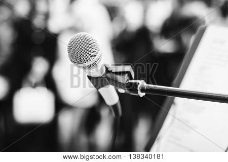 A microphone on a stand among the crowd. Black and white photo.