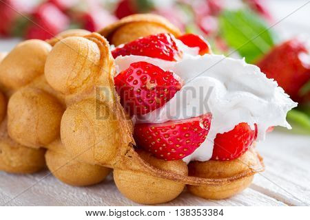 waffles with strawberries and whipped cream on the wooden table