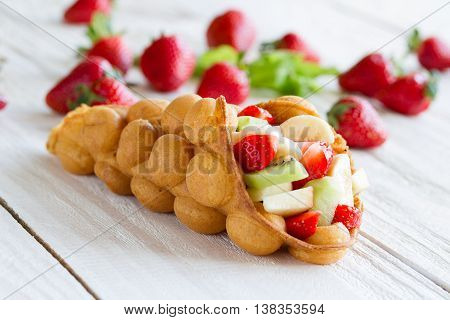 waffles with fruits strawberries apple and kiwi on the wooden table