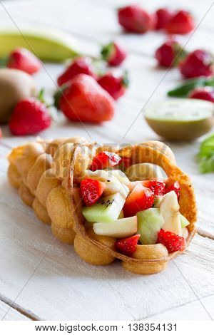 waffles with fruits strawberries apple and kiwi on the wooden table