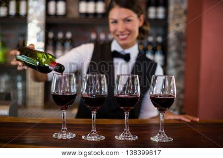 Portrait of bartender pouring a red wine in the glass at bar counter