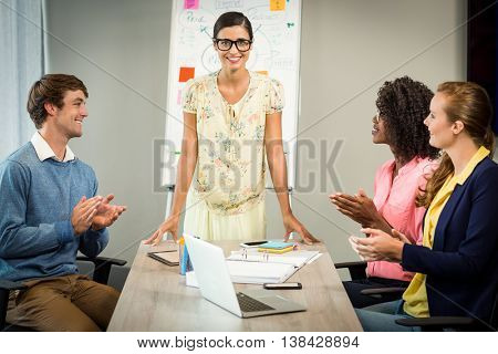 Coworkers applauding a colleague after presentation in the office