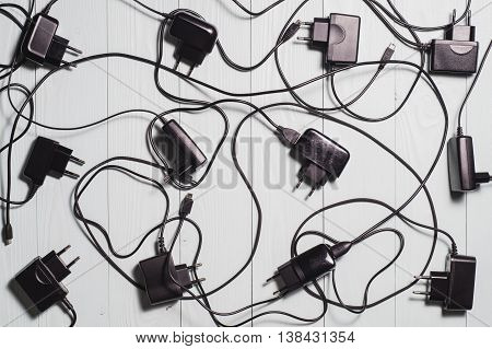 Background of the phone chargers. Used chargers for mobile phones on the wooden background.