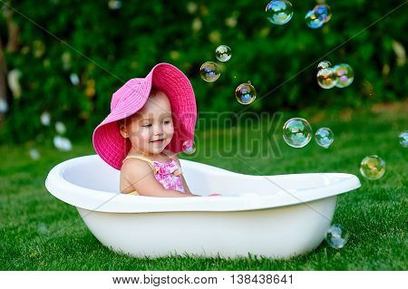 little girl bathes in a bath with soap bubbles.