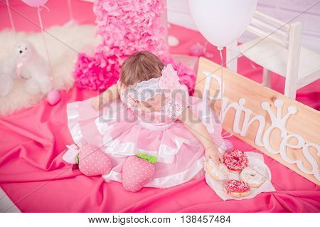 Beautiful little girl in pink dress with sweet cakes