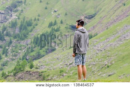 Teenager man with headphones listen to music melacholic at mountain view