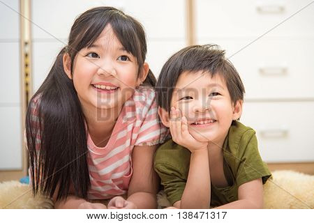 Close up of cute asian child sister and brother lying on the ground.