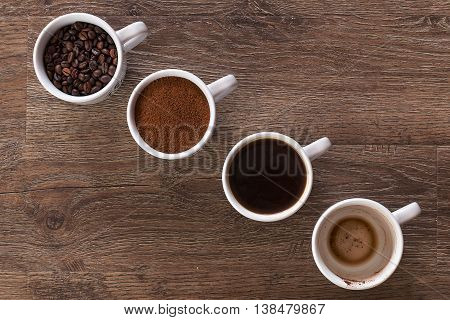 Four cups of coffee, phases of drink - bean, ground and empty cup