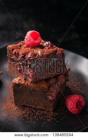 Homemade chocolate sweet brownies cakes with cherry and raspberries on a dark background closeup