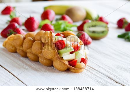 waffles with fruits strawberries apple and kiwi on the wooden table