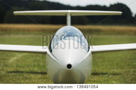 glider at green airfield with blue sky