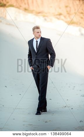 Photo of young businessman in black suit. Blonde hair