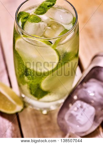 Alcohol drink. On wooden boards is glass with alcohol drink and ice cubes. Drink number hundred fifty six cocktail mohito and scoop ice and quartered lime. Country life cocktail . Top view.
