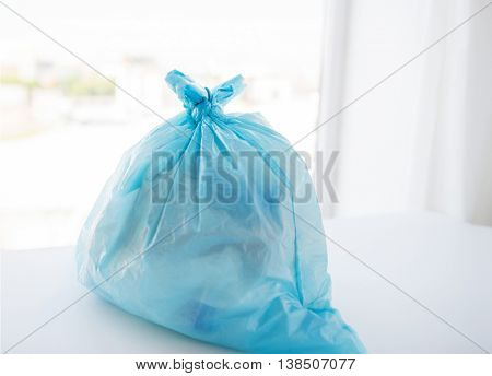 waste recycling, reuse, garbage disposal, environment and ecology concept - close up of rubbish bag with trash or garbage at home