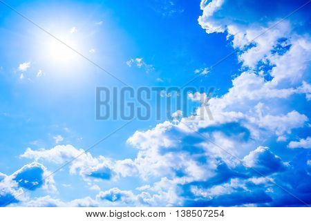 Cear blue sky with fluffy clouds and sunbeams. Beautiful cloudy blue sky background