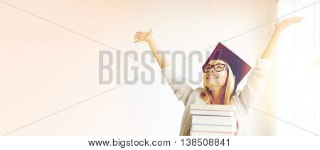 happy student in graduation cap with stack of books