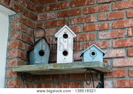 three decorative wooden birdhouses on a shelf
