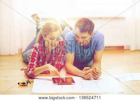 repair, building, renovation and home concept - smiling couple looking at tablet pc at home