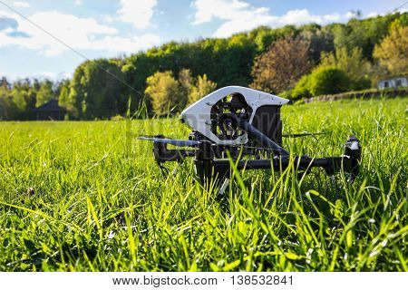Dron is located in the green grass before takeoff. Copter engine is not running. Low point shooting, close-up.