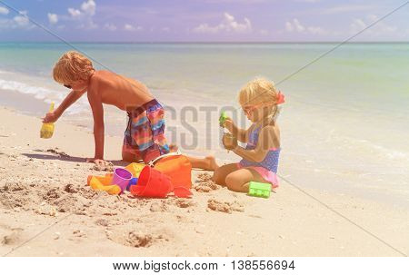 little boy and girl play with sand on summer beach
