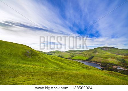 Landscape Scenery Of Green Valley, Hill, River And Cloudy Blue Sky