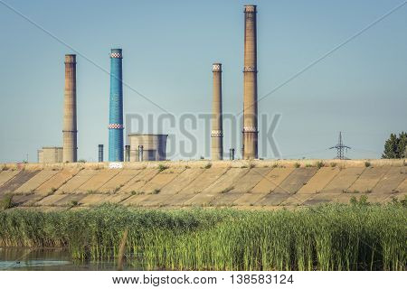 Factory with tall chimneys. Power plant chimneys tower in Bucharest city view from Vacaresti Nature Park.