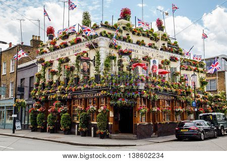 LONDON UK - 28TH JUNE 2016: A view of the outside of the Churchill Arms in London. Large amounts of flowers and UK decorations can be seen on the exterior.