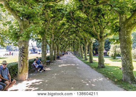FRANKFURT GERMANY - JULY 10 2016: people relax at the benches in the area klein Nizza in Frankfurt Germany. This park area was established in 1910 and is a recreation area for public.