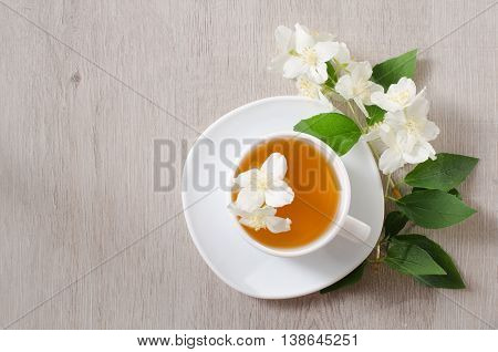 Top view of a mug of herbal tea and jasmine flowers on a wooden table space for text