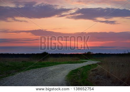 classic countryside landscape with road against dramatic sunset