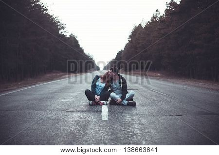 Photo of a boy and girl sits on a road