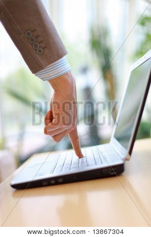 Dedo que señala a un teclado de un ordenador portátil