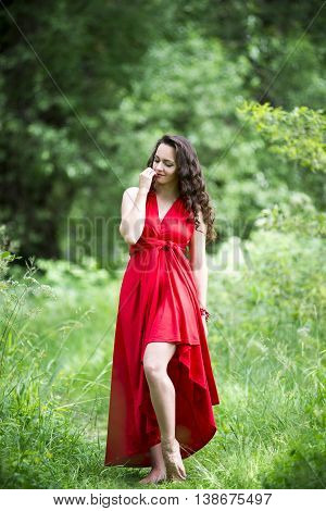 Beautiful young caucasian brunette woman in red dress outdoors whole-length portrait