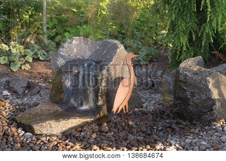 A custom built rock fountain next to a flat crane sculputure
