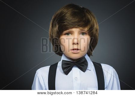 Closeup Portrait of handsome boy with astonished expression while standing against grey background.