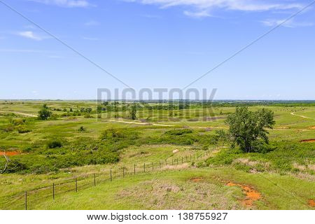 CANTON, KANSAS, USA - MAY 17, 2015: Overlook of the Maxwell Wildlife Refuge near Canton with rolling hills and some trees in the back a buffalo herd is grazing.