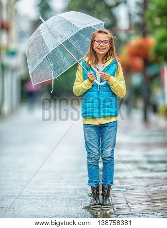 Portrait of beautiful young pre-teen girl with umbrella under rain.