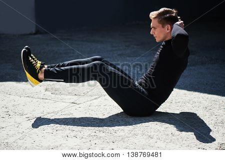 Athletic male in tight clothes makes exercise for the press