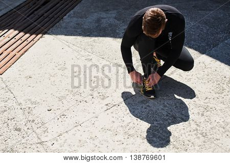 Male athlete tying laces on athletic shoes