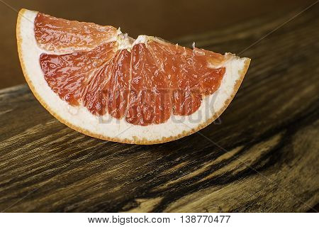 Slice of red juicy grapefruit on an old wooden board