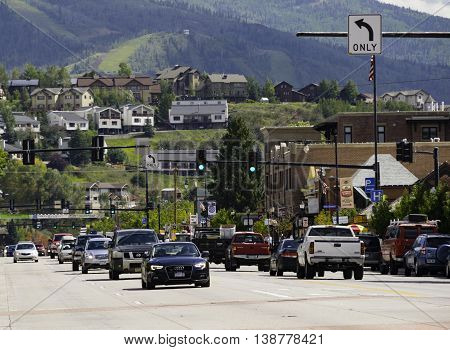 Steamboat Springs CO USA Sept 10 2014 Cars drive on the Main road of the resort town Steamboat Springs Colorado with the Rocky Miuntains in the background