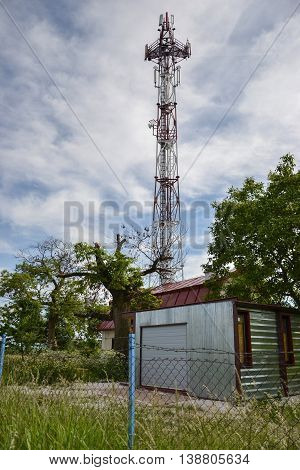 Base transceiver station (BTS) with antenna isolated on blue sky background. Telecommunications radio tower cells