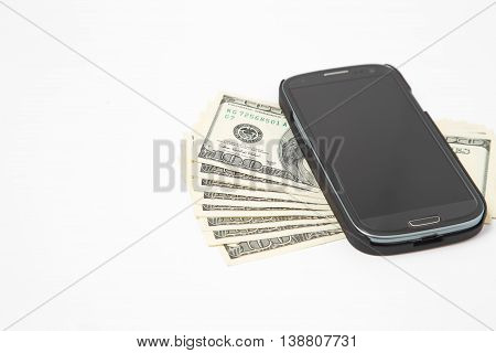 Smartphone lying on the United States dollars, isolated on a white background