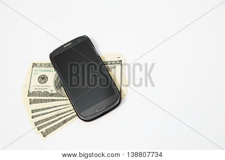 Smartphone lying on the United States dollars, isolated on a white background