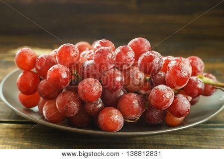 Bunch of red grapes on a plated on dark background