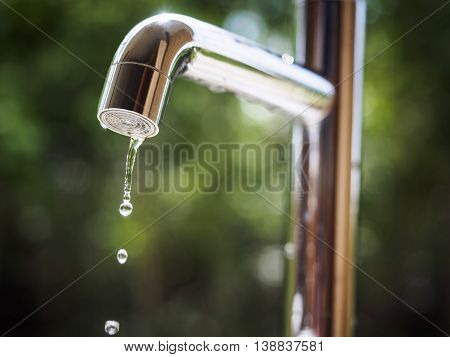 Water tap with water drop Blur outdoor Green park background