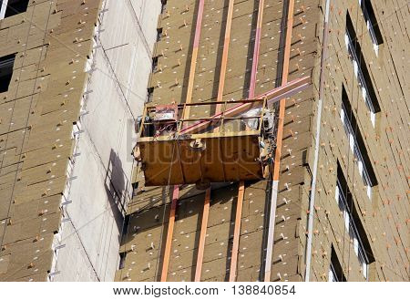 construction suspended yellow cradle with workers on a newly built high-rise building in Moscow