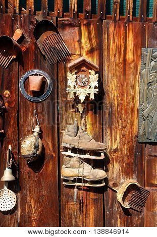 antique old style retro object assemblage on a wooden wall. rustic stile. Rake in blueberries, clock, bell, art, old skates and others