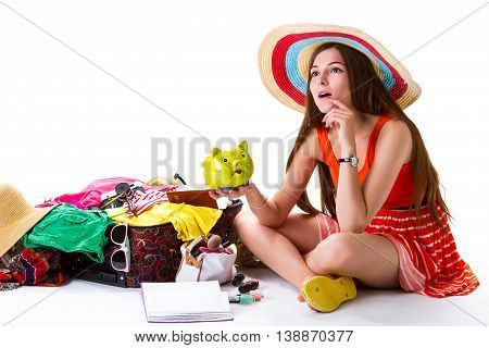 Girl sits beside overfilled suitcase. Lady with green money box. Best idea for vacation. Need some time to think.